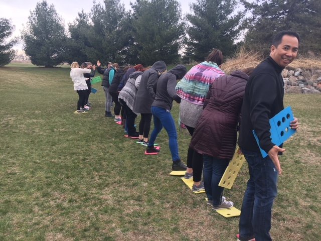 A corporate retreat group gathers in a clearing for a team building exercise